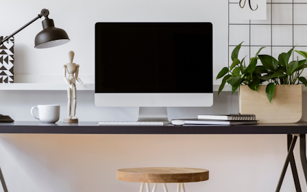 A desk with a computer and lamp.