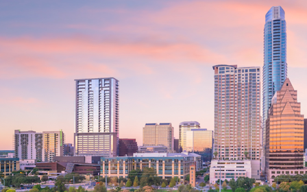 A city skyline with a pink and purple sky.