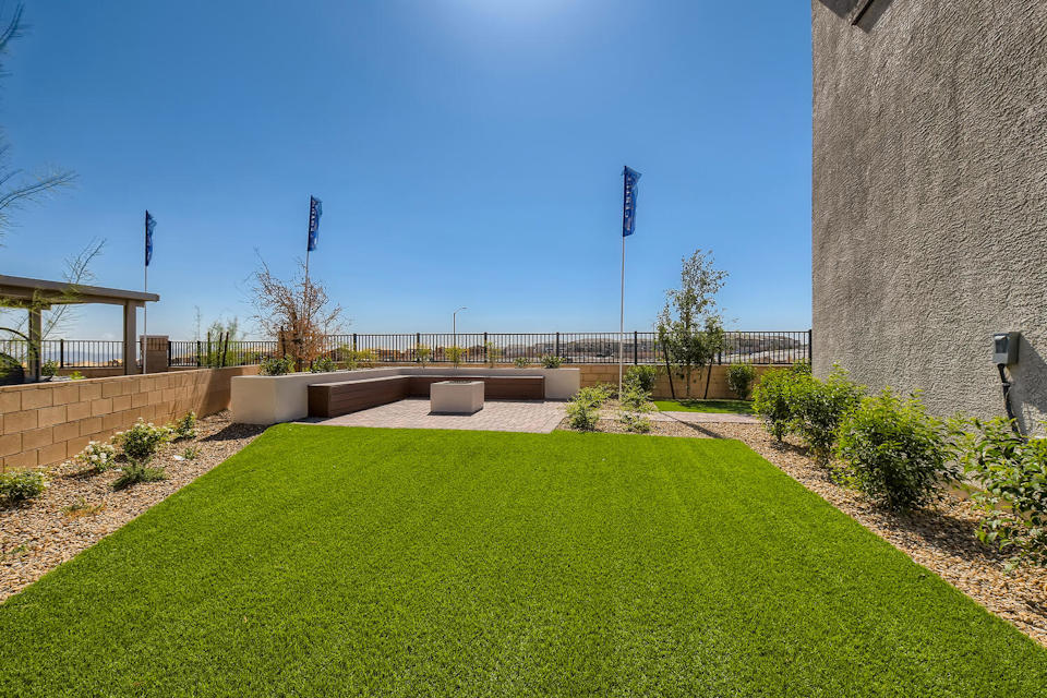 A grassy area with a stone wall and a building in the background.