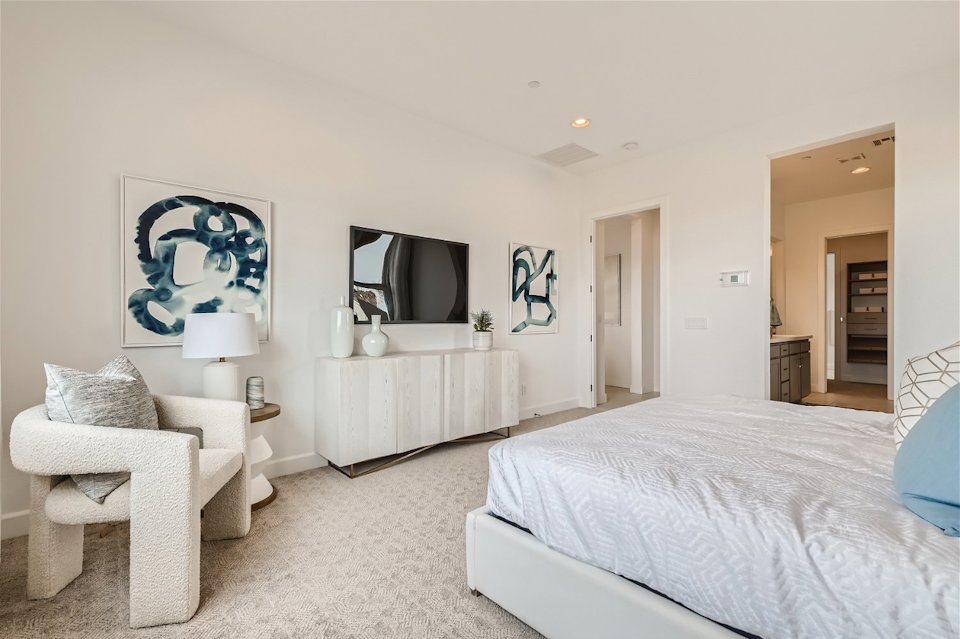 A bedroom with a bed and a chair.