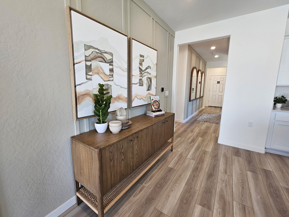A room with a wood floor and a wood cabinet with a painting on it.