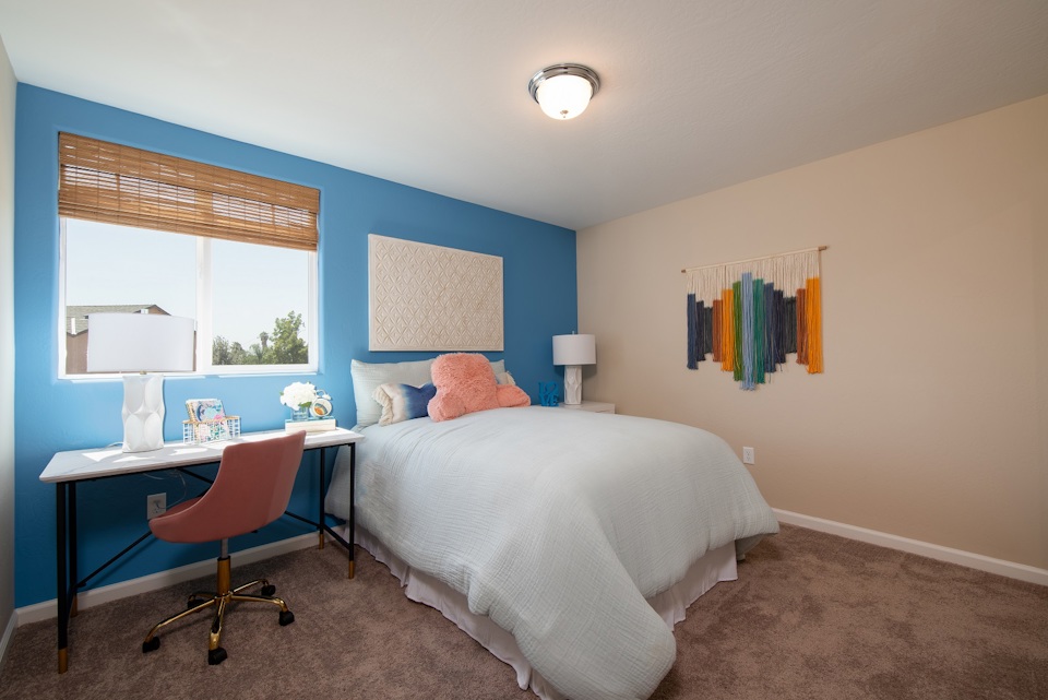 A bedroom with a bed desk and a chair.