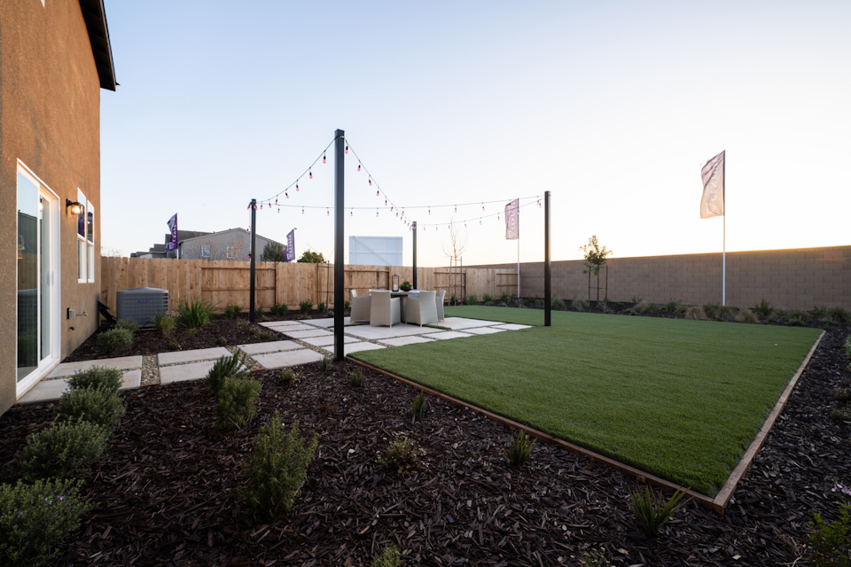 A grassy area with a fence and a building in the background.