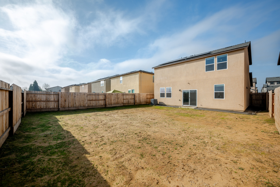 A dirt yard with a fence and a building in the background.