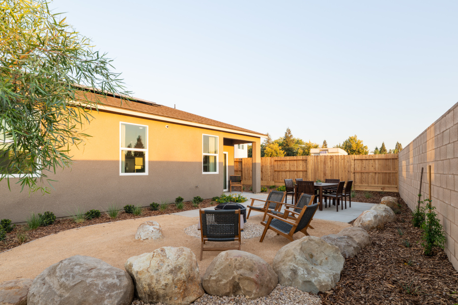 A backyard with a table chairs and a house.