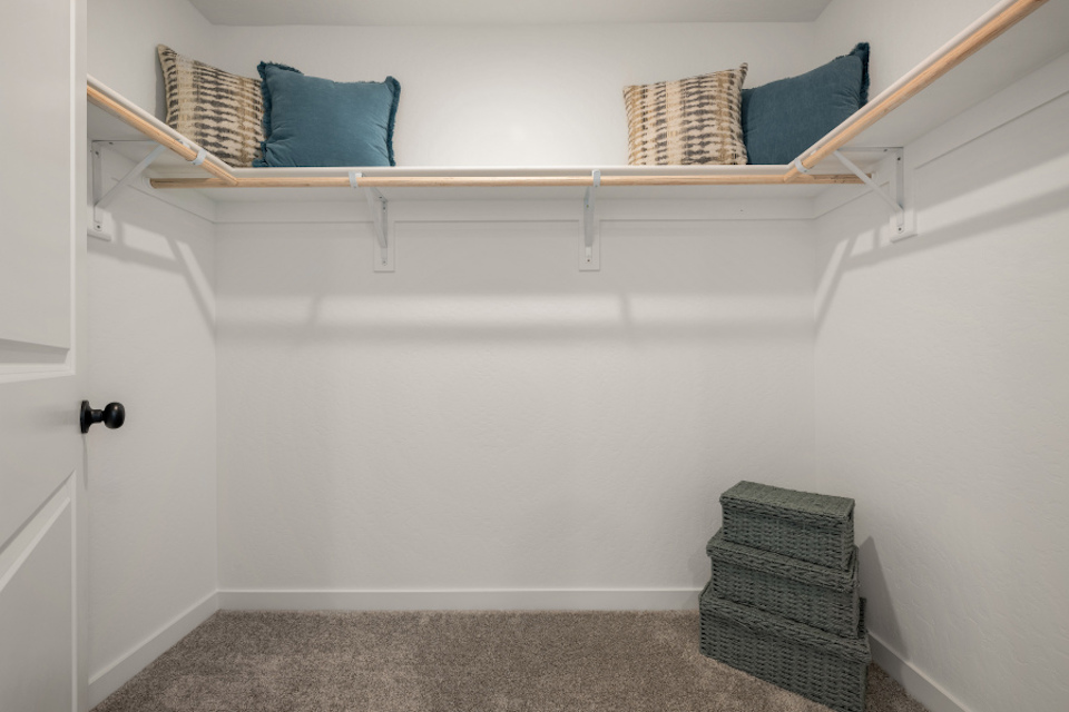 A shelf with baskets and pillows.