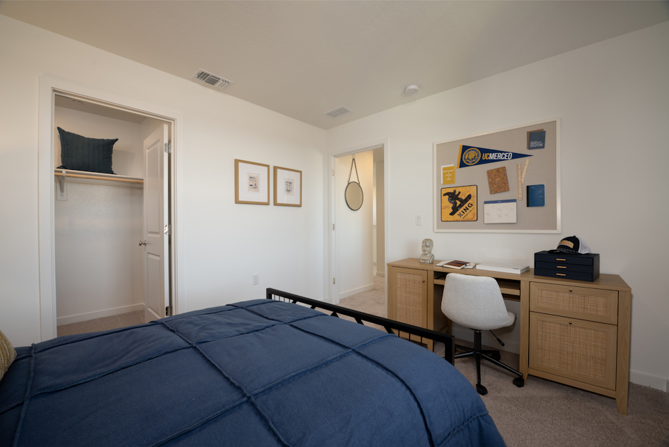 A bedroom with a bed desk and a chair.