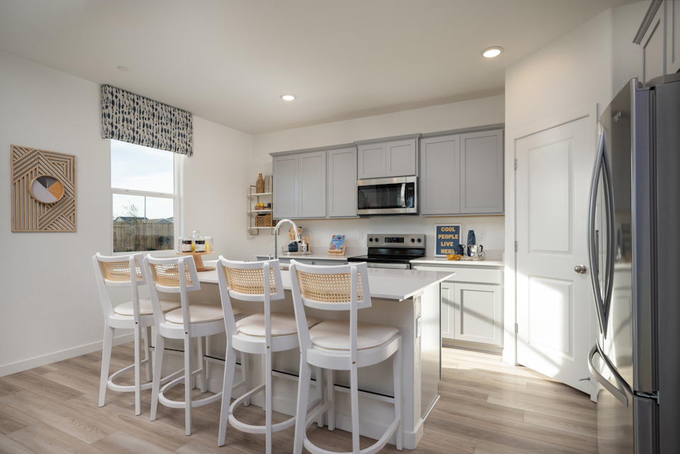 A kitchen with white chairs.