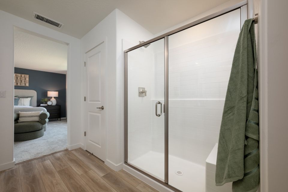 A bathroom with a shower unit and a bed.