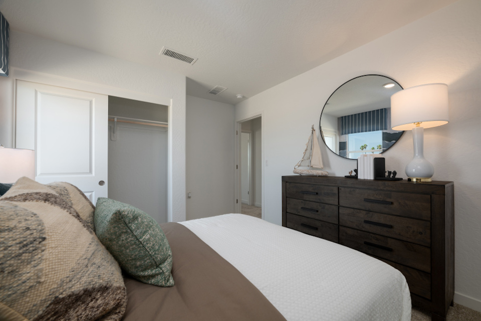 A bedroom with a bed and a mirror.