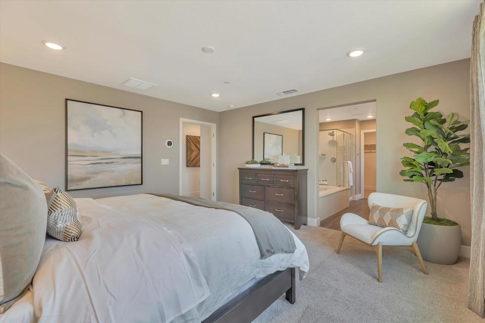 A bedroom with a bed and a chair.