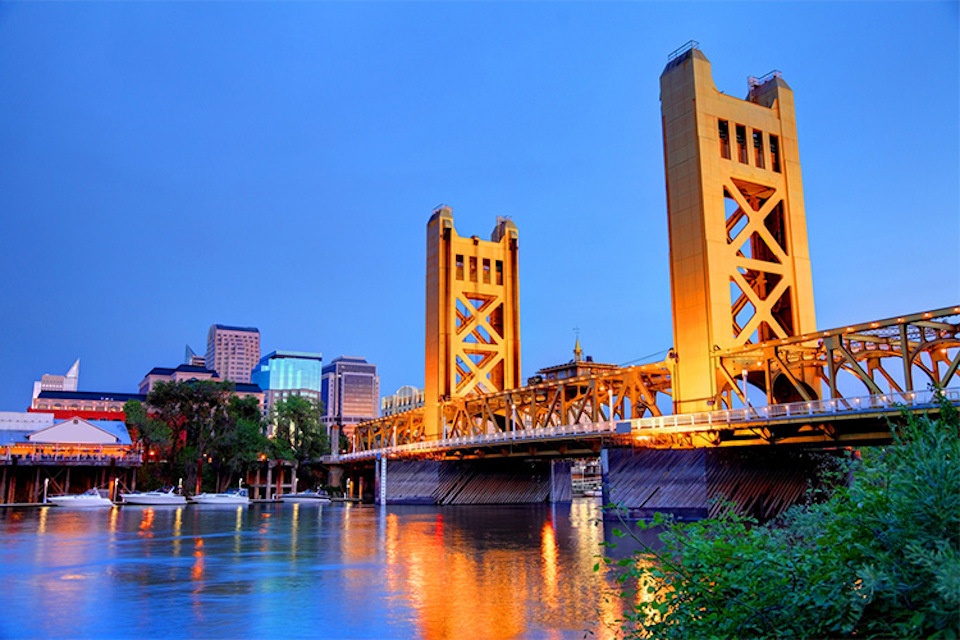 A bridge over a river with buildings in the background.