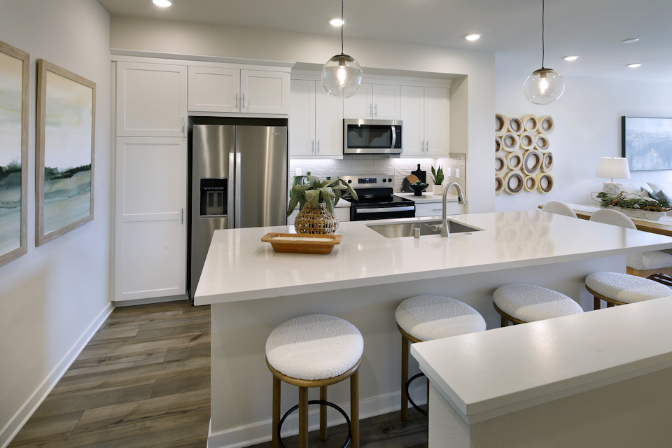A kitchen with a bar stool and a white counter top.