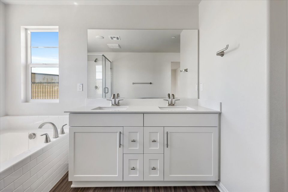 A bathroom with a tub sink and mirror.