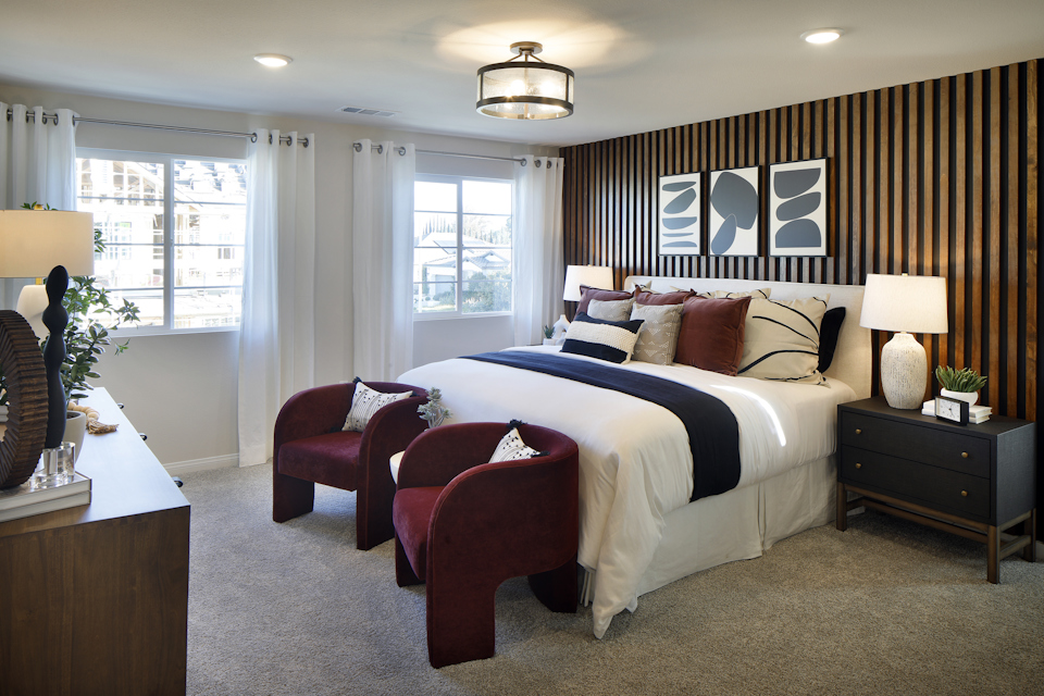 A bedroom with a bed and chairs.