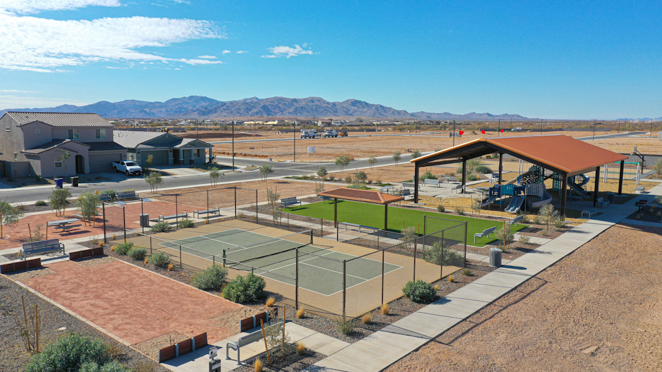 A large empty courtyard with a fence and a building in the background.
