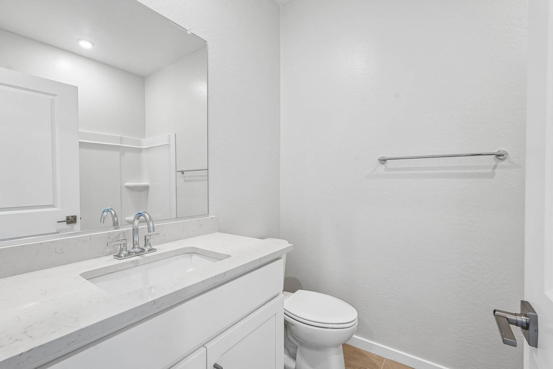 A bathroom with a sink toilet and mirror.