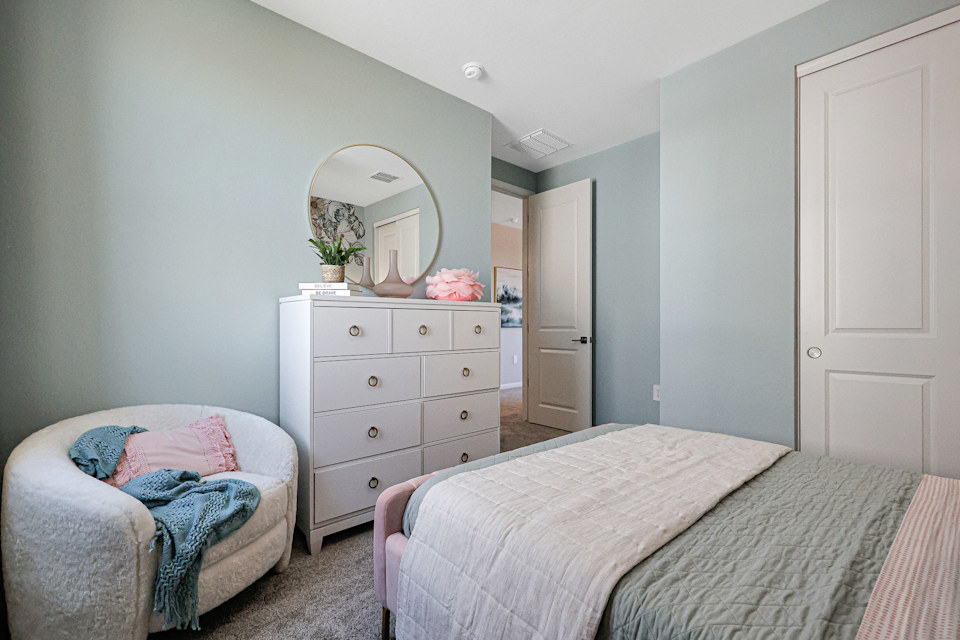 A bedroom with a mirror and a bed.