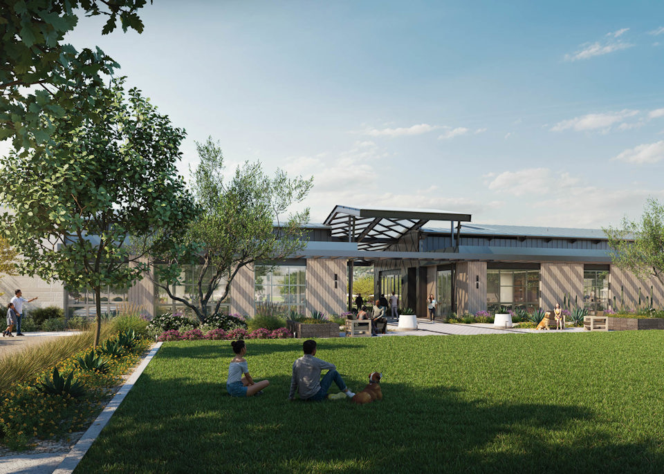 A group of people sitting on the grass in front of a building.
