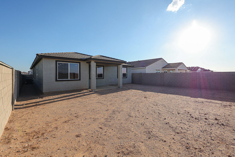 A dirt yard with a house in the background.