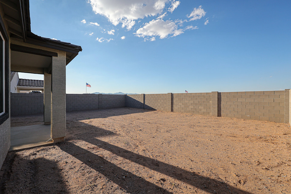 A dirt road with a building on the side.