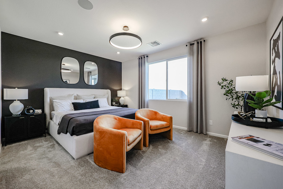 A bedroom with a bed and chairs.