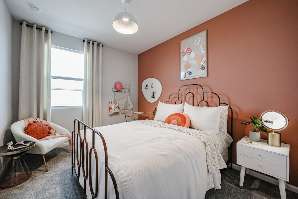 A bedroom with a bed and a chair.