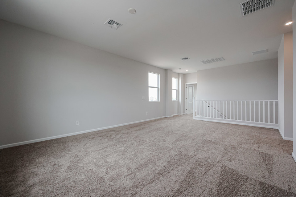A room with a carpet and a white railing.