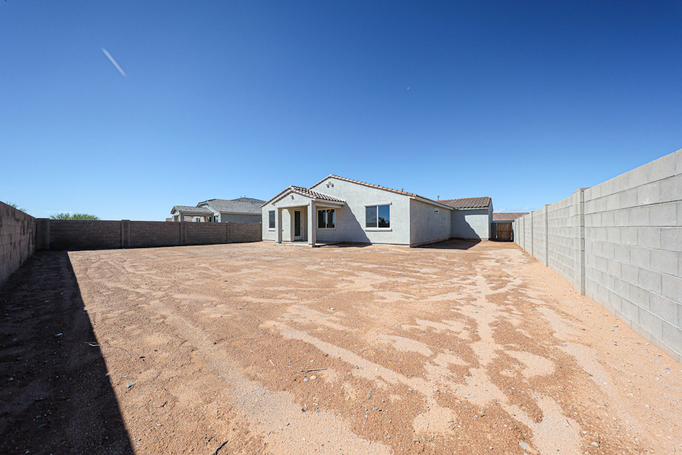 A dirt road with a building on the side.