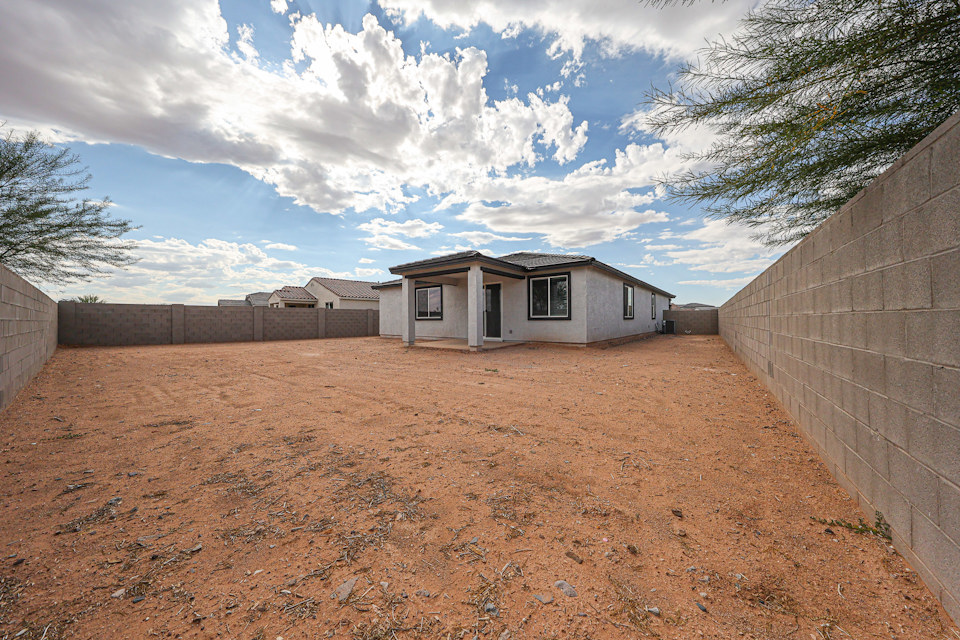 A dirt yard with a house in the background.