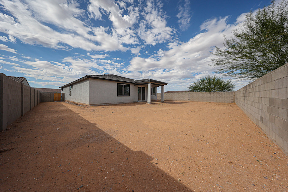 A dirt road with a house on the side.