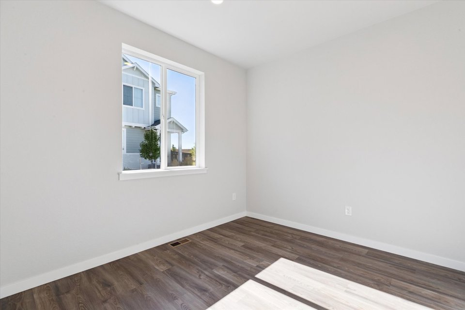 A room with a wood floor and a window with a plant in it.