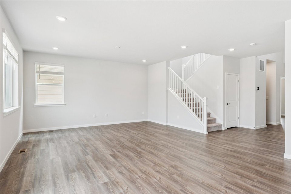 A large empty room with a wood floor and white walls.