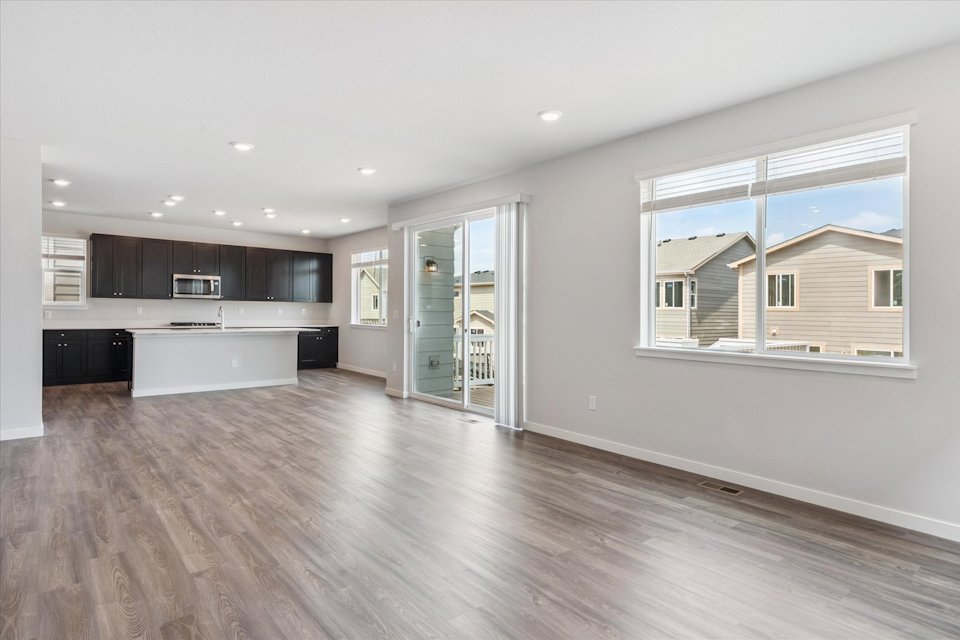 A large empty room with a wood floor and a glass door.