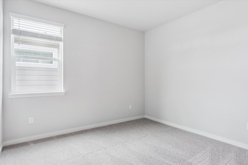 A room with a window and a white wall.