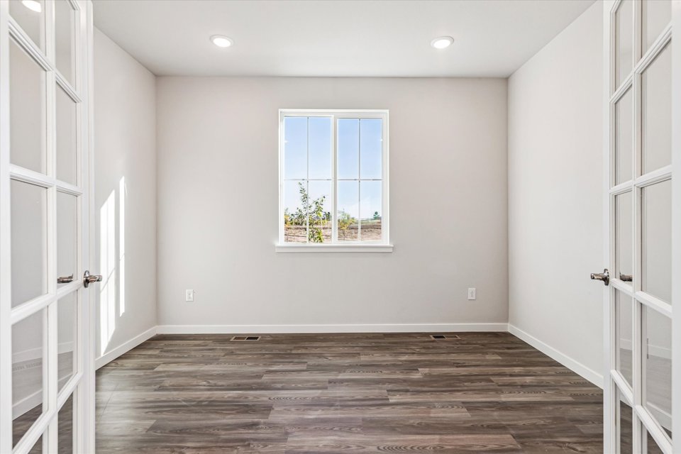A room with a window and a wood floor.