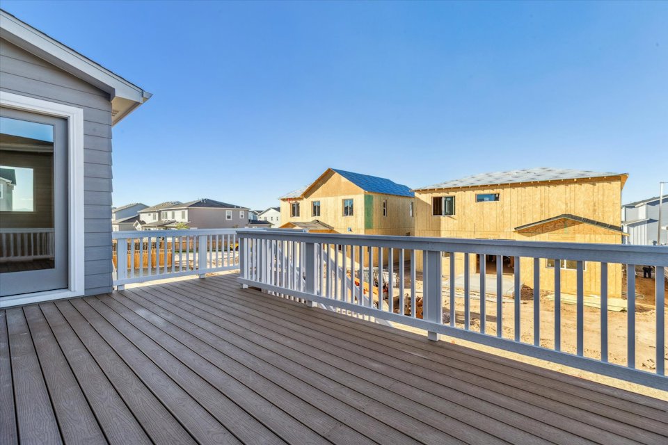 A deck with a railing and buildings in the background.