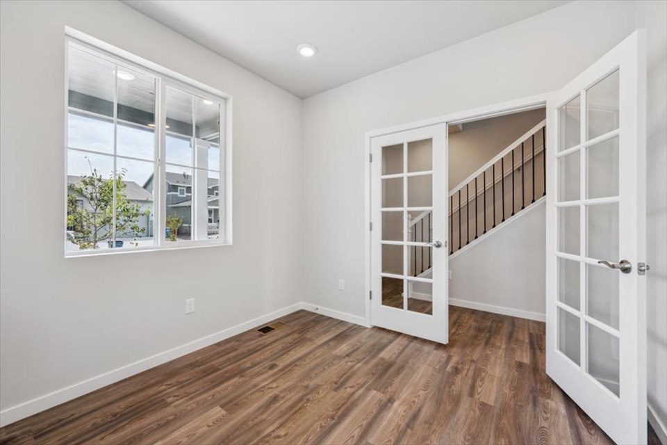 A room with a wood floor and a window with a door.