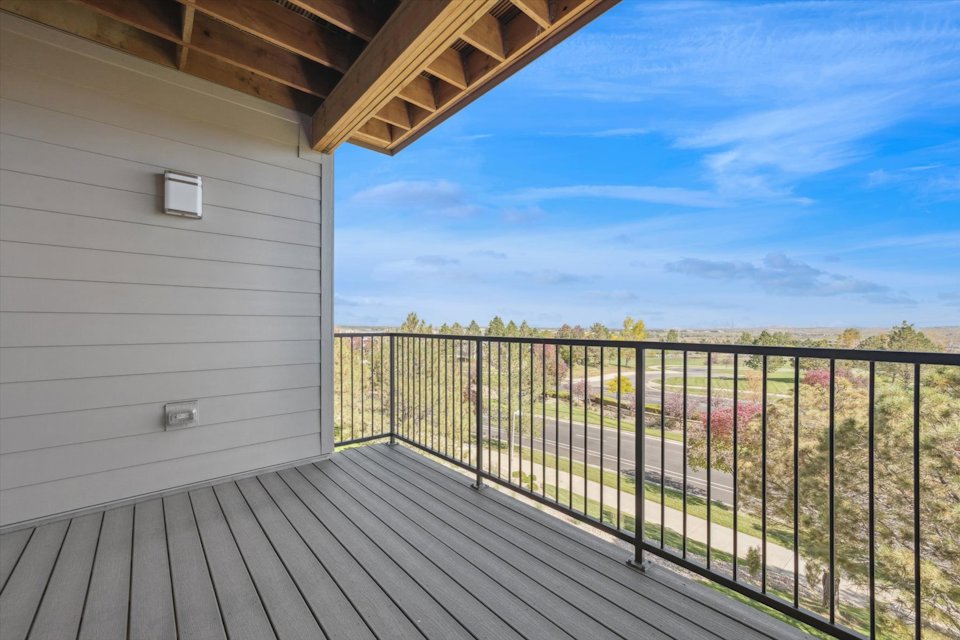 A deck with a railing and a building with a view of the ocean.