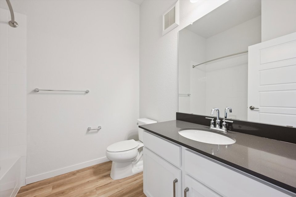 A bathroom with a sink toilet and mirror.