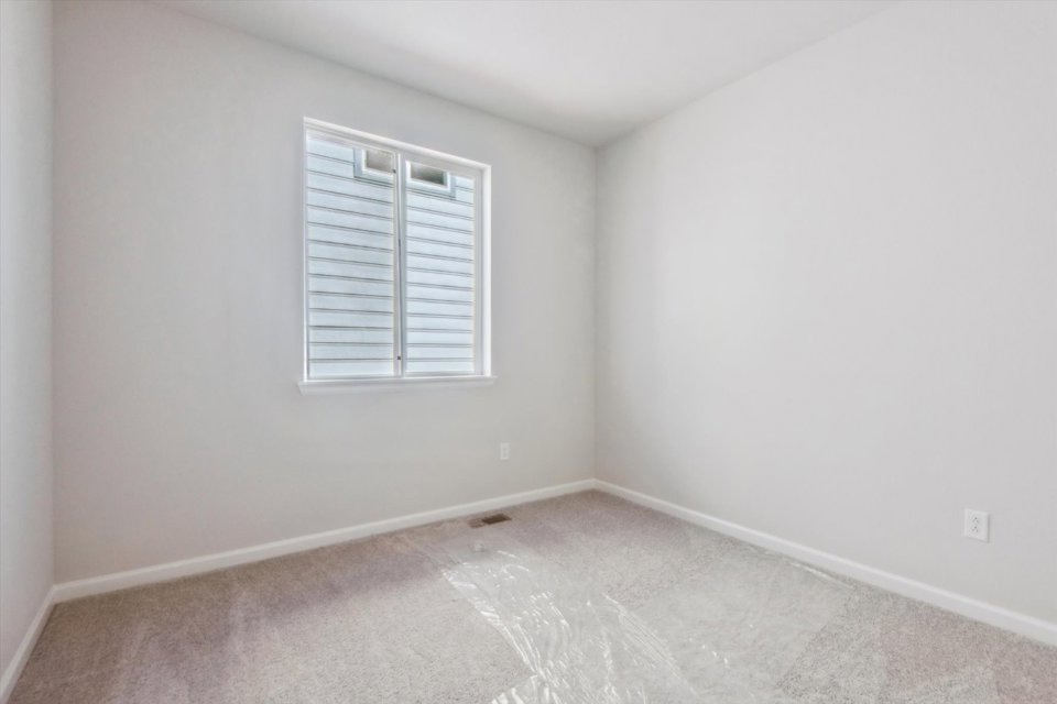 A room with a window and a rug.