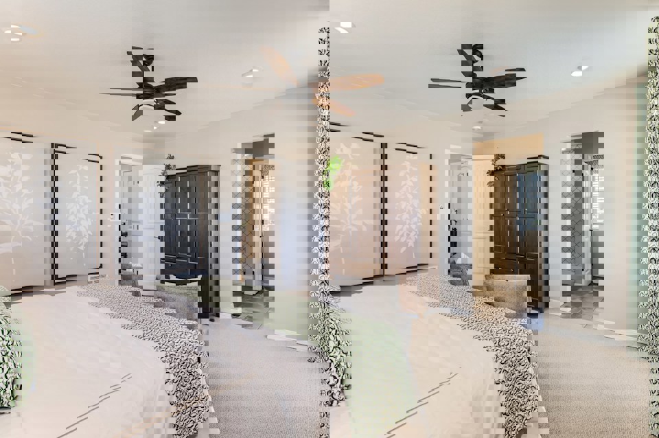 A bedroom with a bed and a fan.