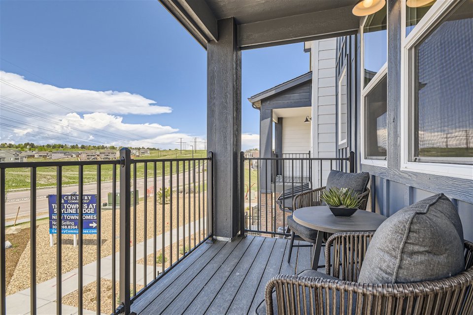 A deck with a table and chairs on it and a view of the mountains and the ocean.