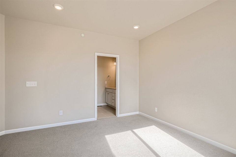 A room with a white tile floor and a white wall with a door.