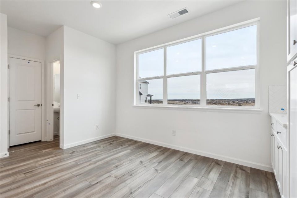 A room with a wood floor and a window with a view of the city.