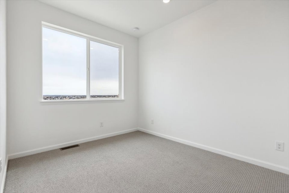 A room with a window and a white wall.