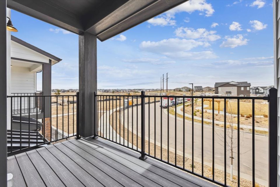 A deck with a fence and a building in the background.