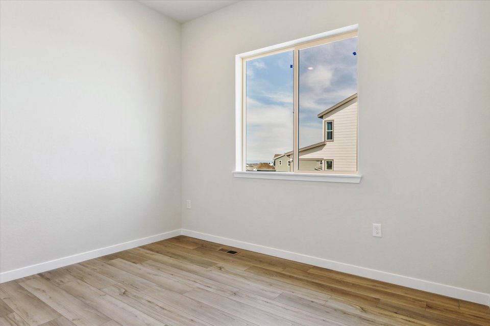 A room with a window and a wood floor.