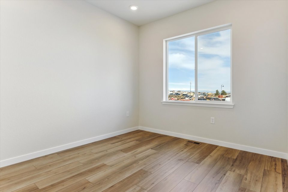 A room with a window and a wood floor.