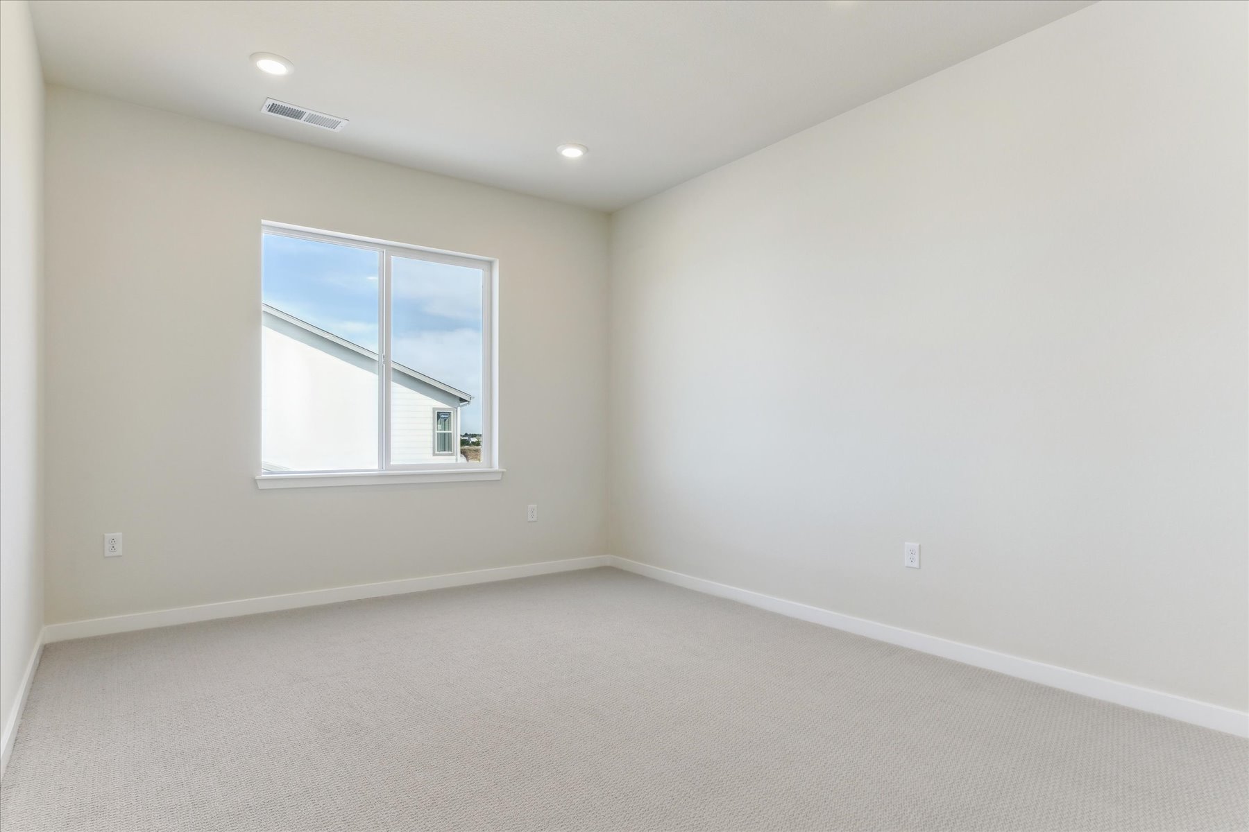 A room with a window and a white wall.